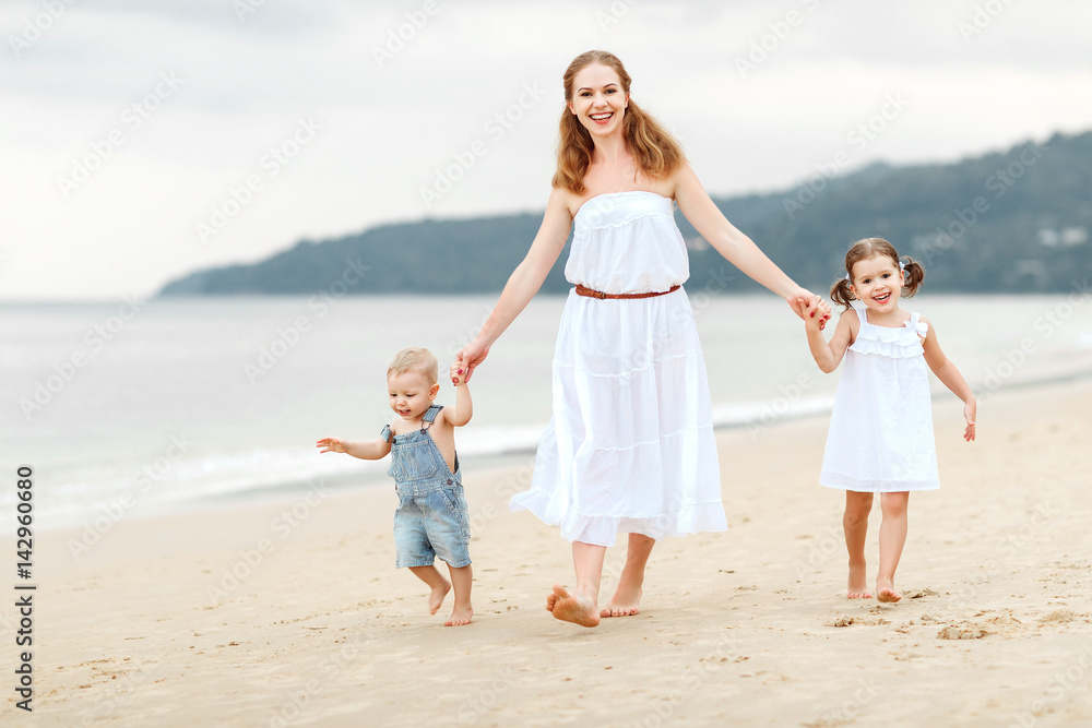 快乐的家庭母亲和孩子在夏天海边的海滩上