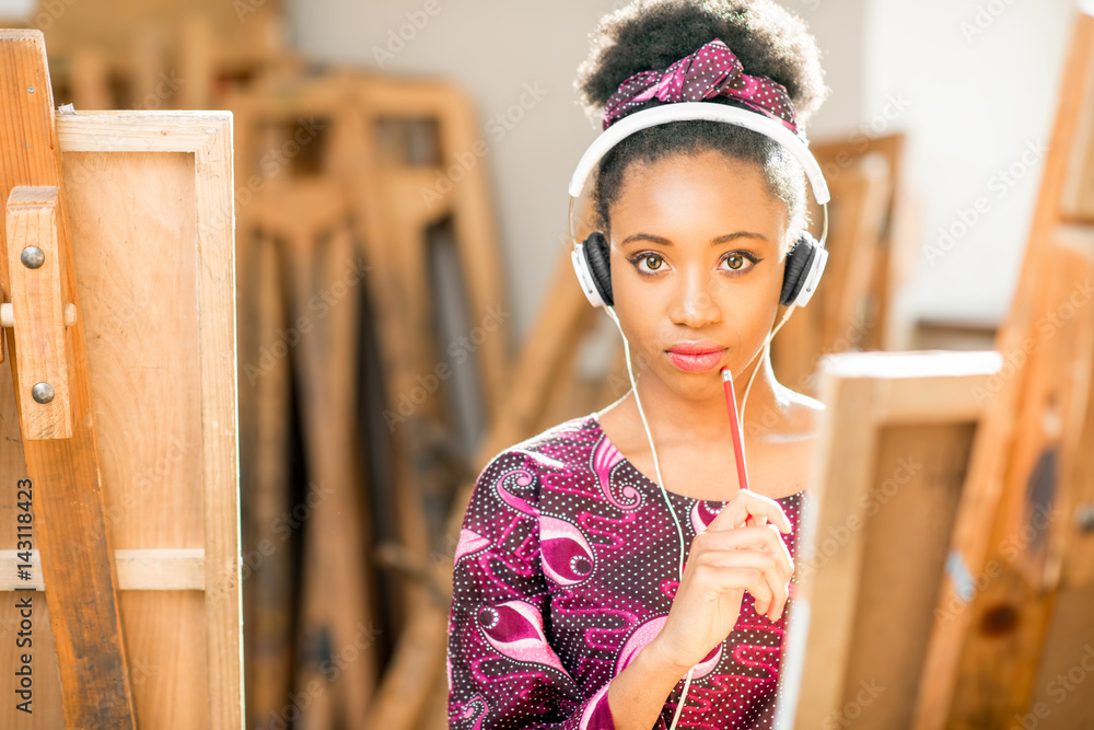 年轻的有创造力的非洲裔学生在大学画室的画架上画画