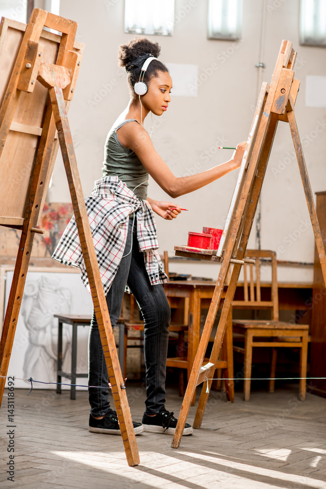 年轻的有创造力的非洲裔学生在大学画室的画架上画画