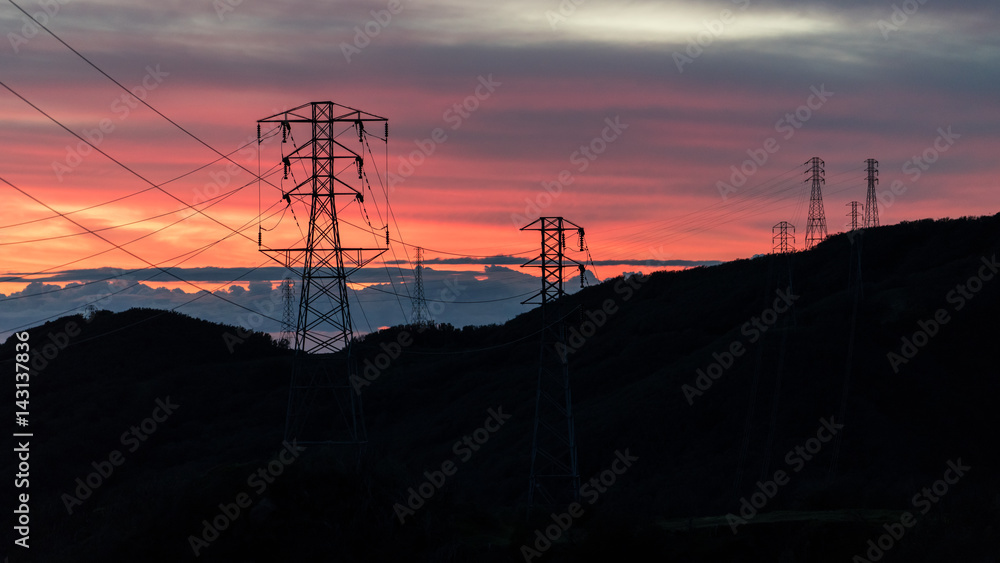 日落在海洋山脉上剪影电力线塔的形状