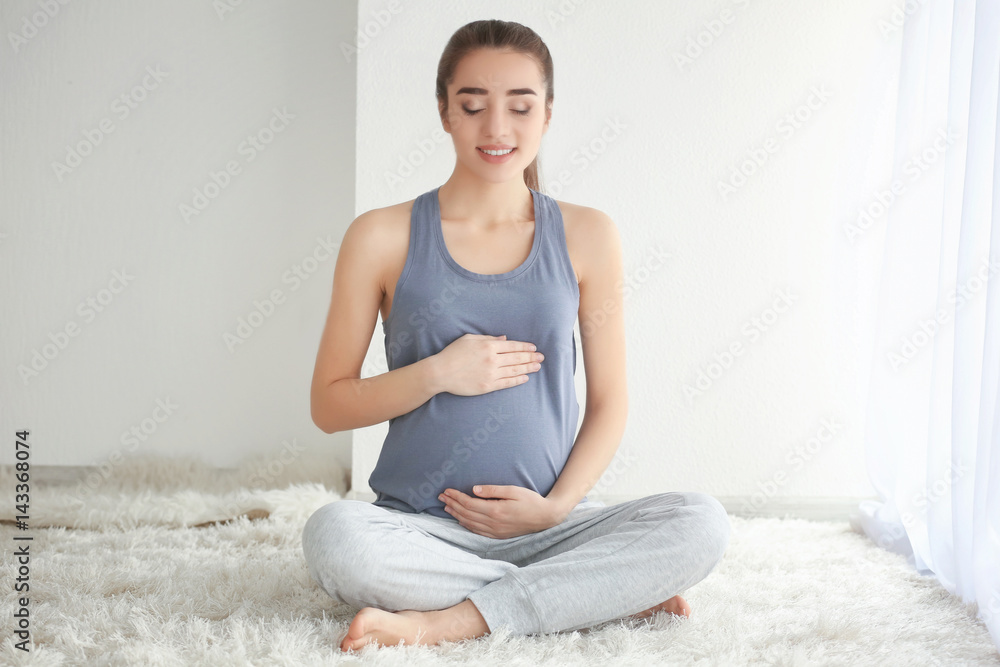 漂亮的孕妇坐在家里的地板上