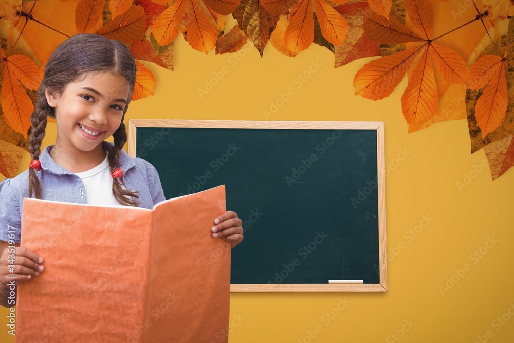 女学生拿着书对着黑板和树叶