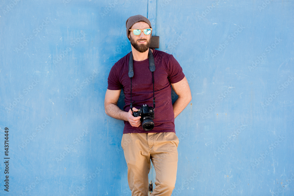 一位时尚摄影师的肖像，穿着休闲的t恤，戴着帽子，站在画布上，相机