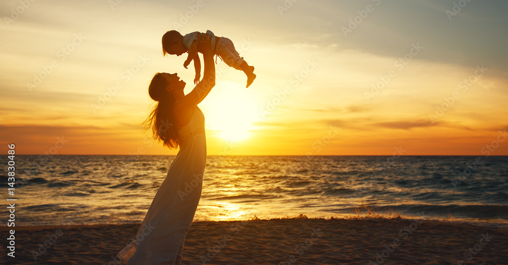 快乐的家庭母亲带着小儿子在夏天的海滩上海边散步