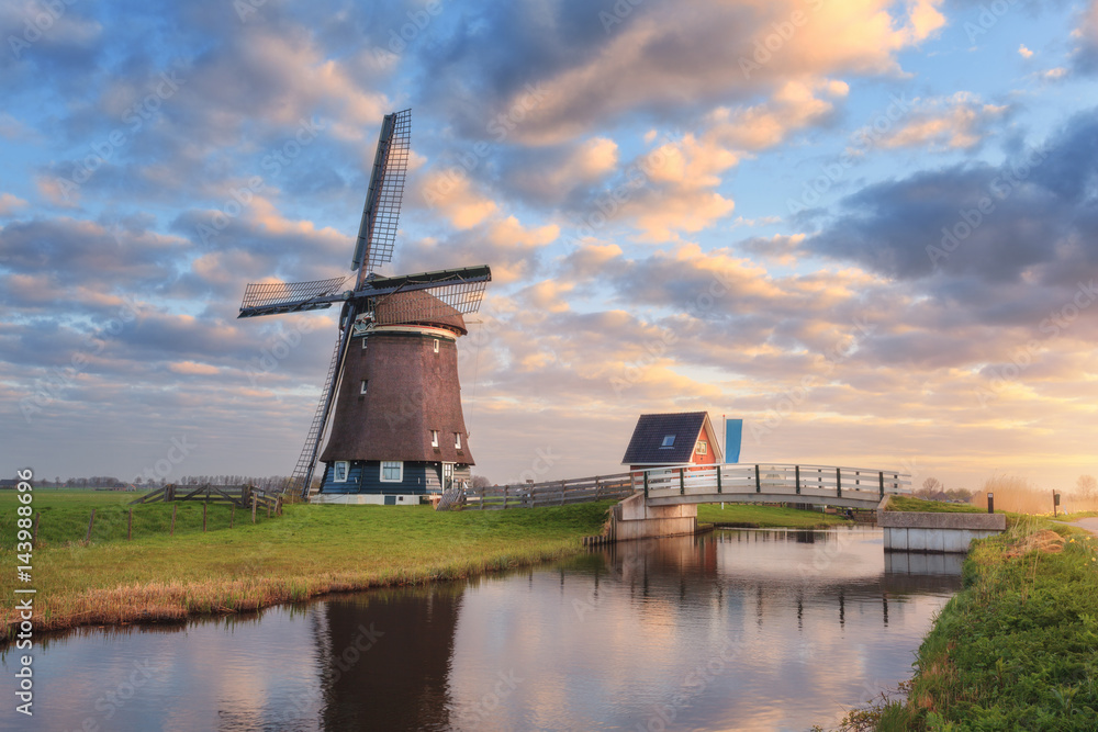 荷兰日出时运河附近的风车。美丽的古老荷兰风车和五颜六色的s