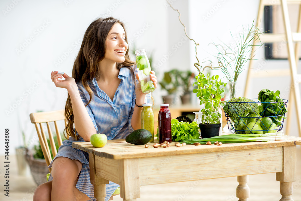 美丽的女人坐在家里享用健康的绿色食品和饮料。素食和排毒概念