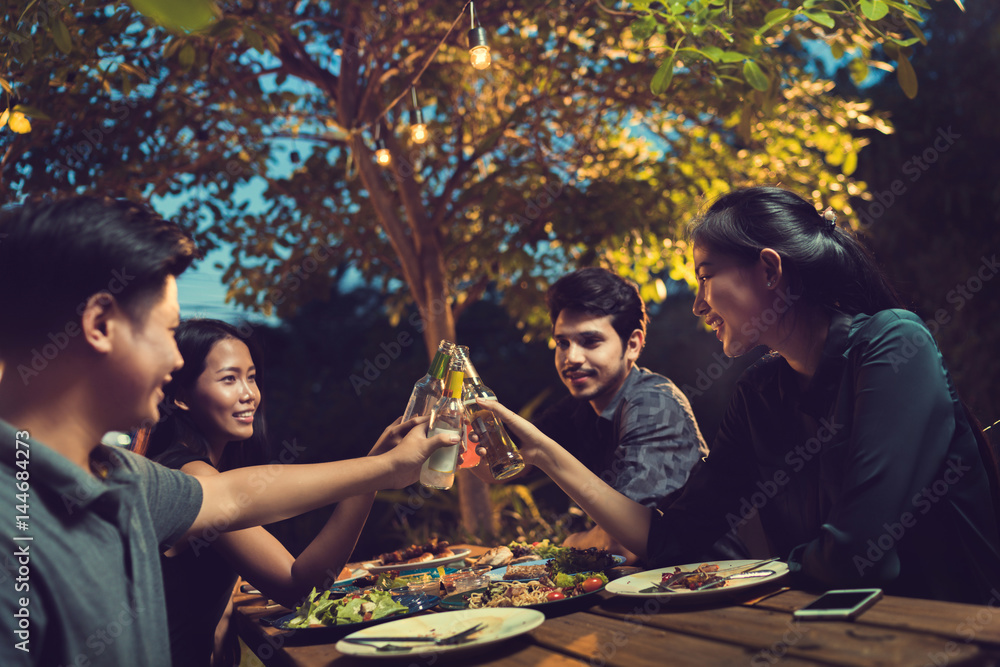 亚洲人在庆祝节日，他们在户外碰杯啤酒和吃晚饭，他们很开心