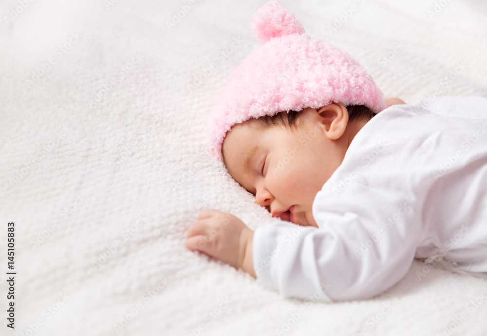 可爱的新生女婴躺在床上。两个月大的婴儿睡在白色柔软的毯子上
