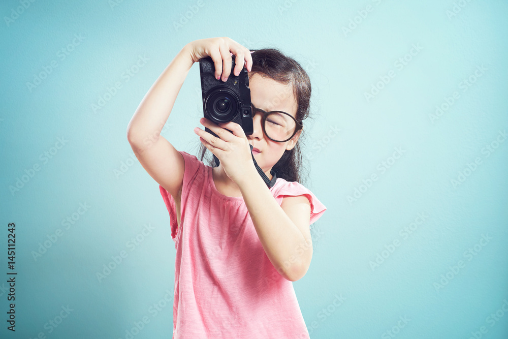 Portrait of cute asian little girl taking picture with retro camera in the studio on vintage mint gr