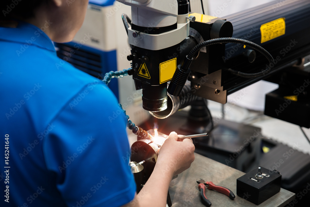工人在工厂用激光焊机焊接修理模具和模具零件。