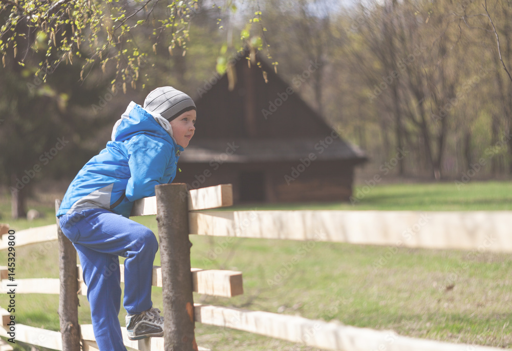 早春时节农场围栏上的小男孩