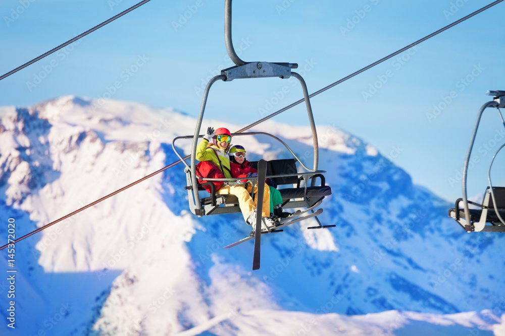 两名滑雪者顶着雪山在电梯上滑雪