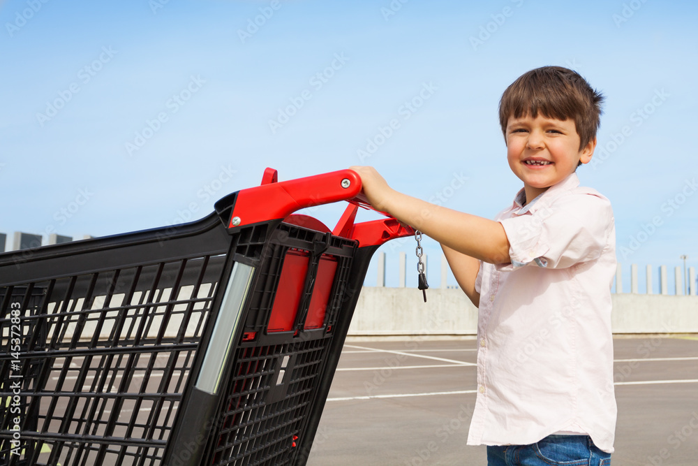 微笑男孩推着购物车去超市