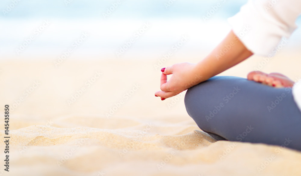 女人的手在海滩上练习瑜伽和冥想。