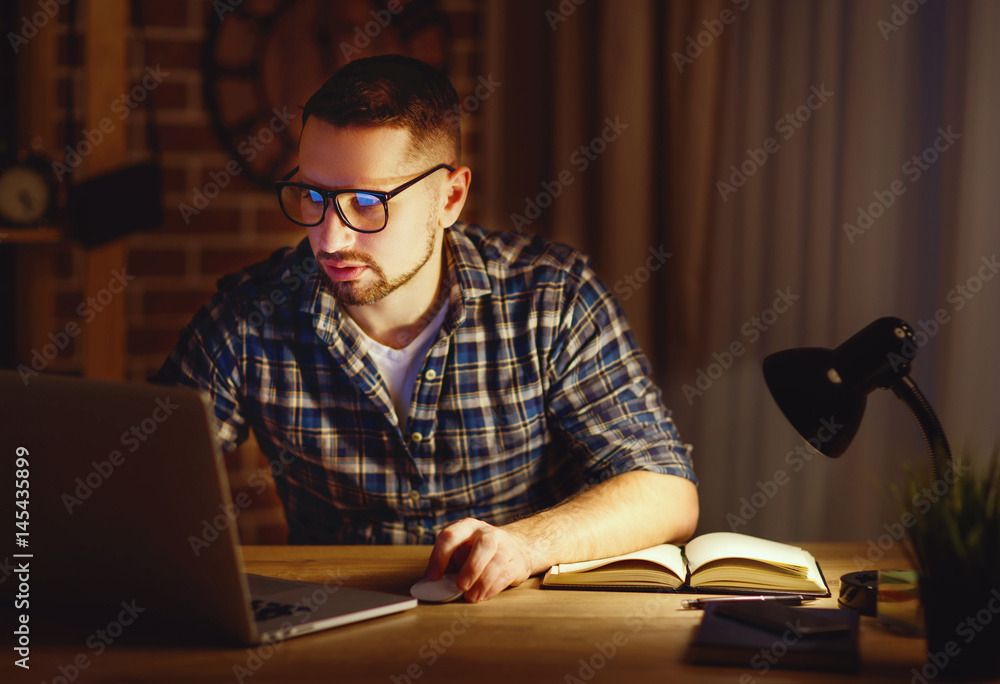 man working on computer at home at night in dark
