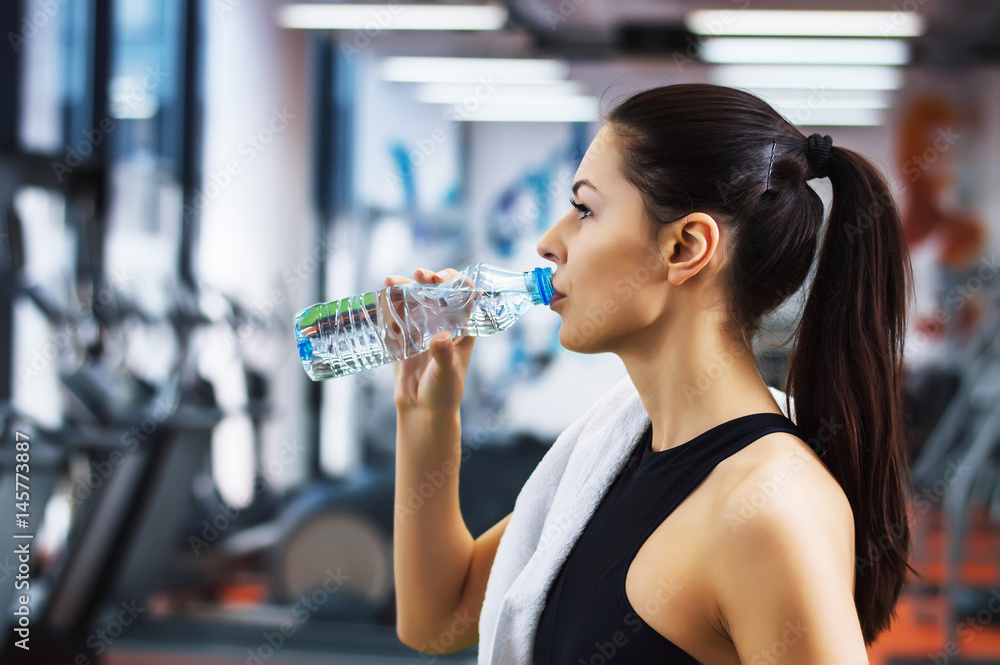年轻女子在健身房喝水