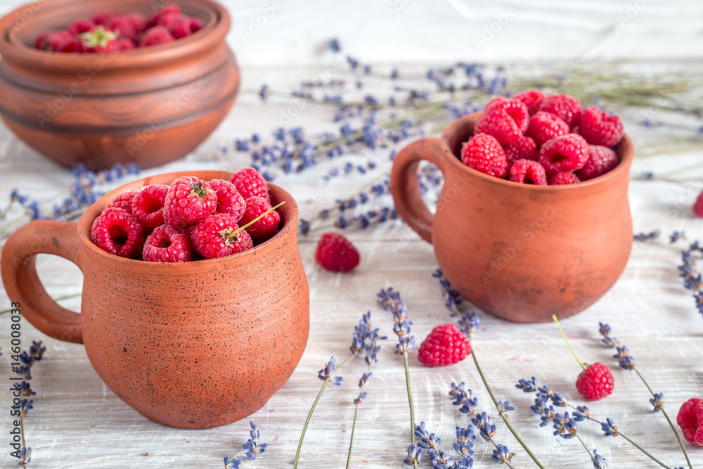 raspberry in pottery cup with lavander on wooden background