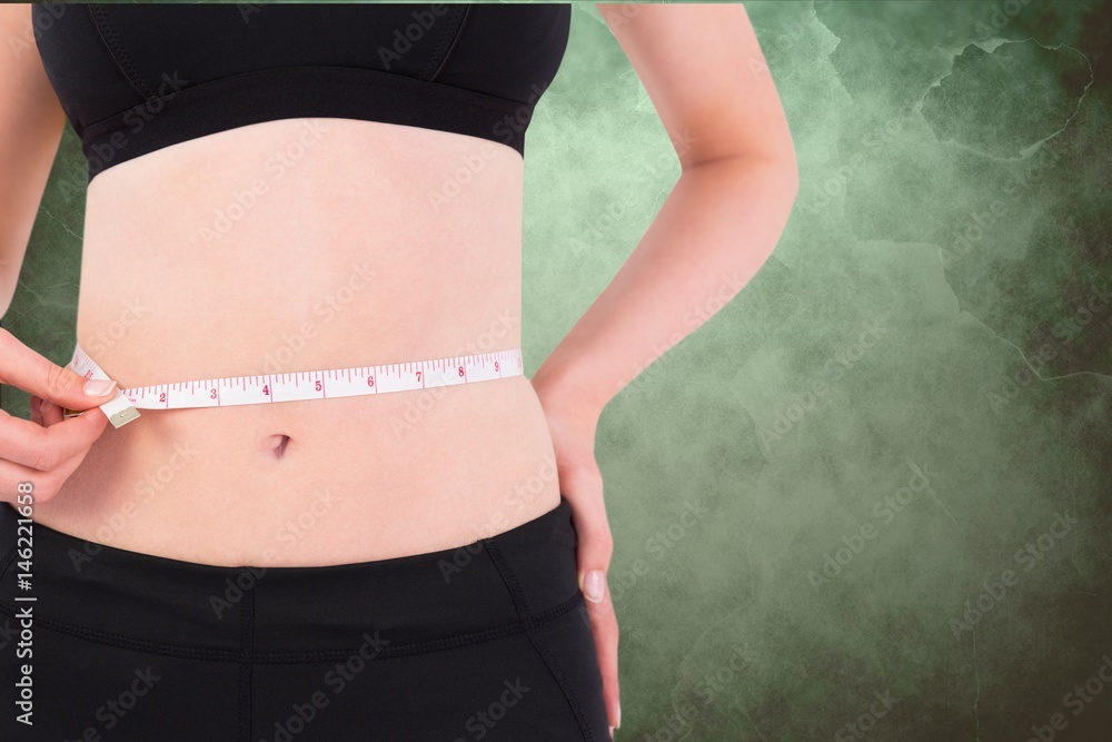 在绿色背景下测量腰部的女性腹部