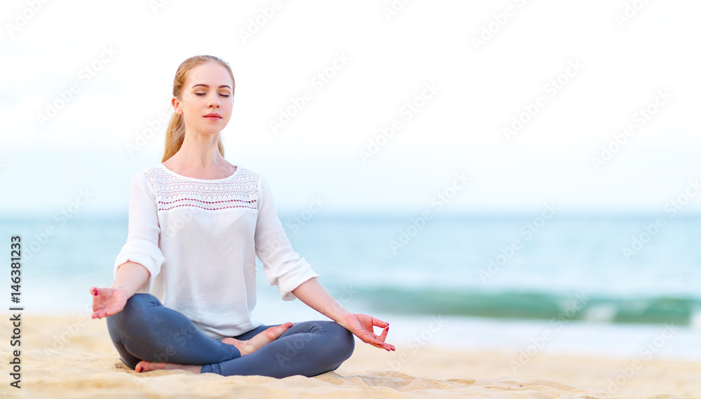 一位女士在海滩上练习瑜伽并以莲花姿势冥想。