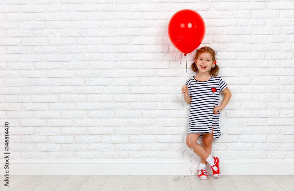 快乐有趣的小女孩，砖墙附近有一个红球。