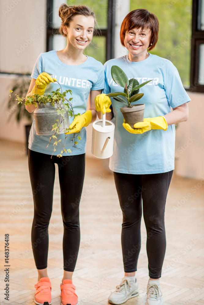 Young and older volunteers dressed in blue t-shirts taking care of green plants indoors