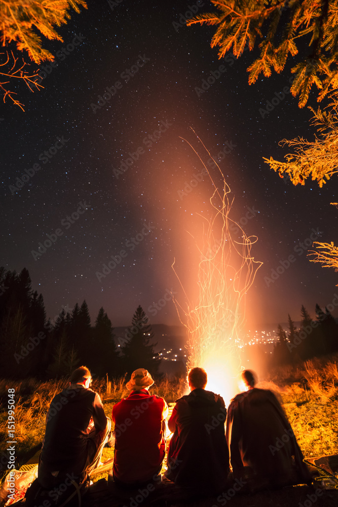 四个朋友坐在篝火旁