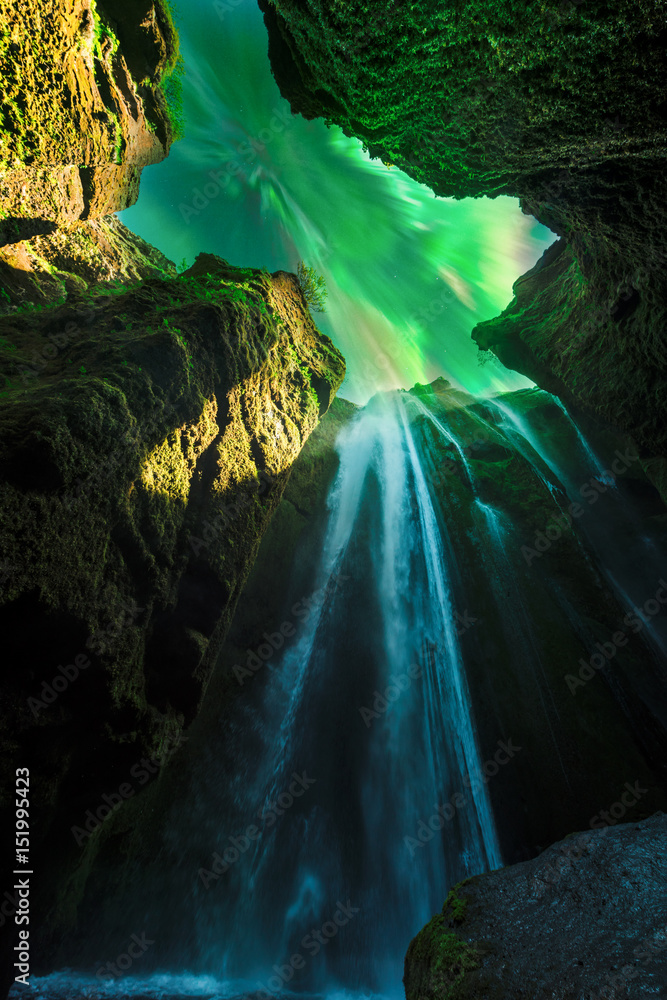 Green aurora light behind unique Gljufrabui waterfall