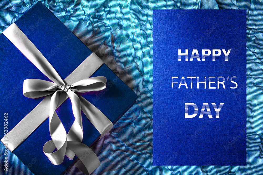 带缎带装饰的深蓝色礼盒，波尔卡蓝纸上写着父亲节快乐的信息，