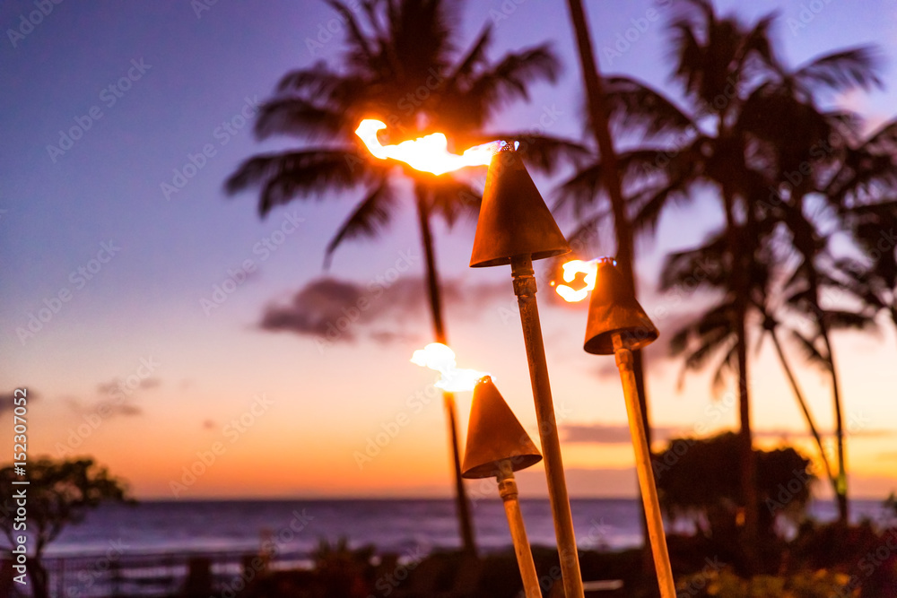 带着火把的夏威夷日落。夏威夷偶像，黄昏时海滩度假胜地或餐厅的灯光闪烁