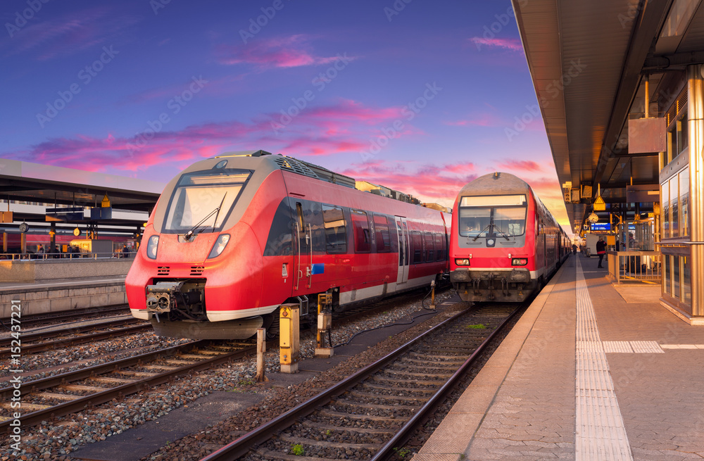 火车站上的高速红色通勤列车和欧洲日落时的彩色天空。工业l