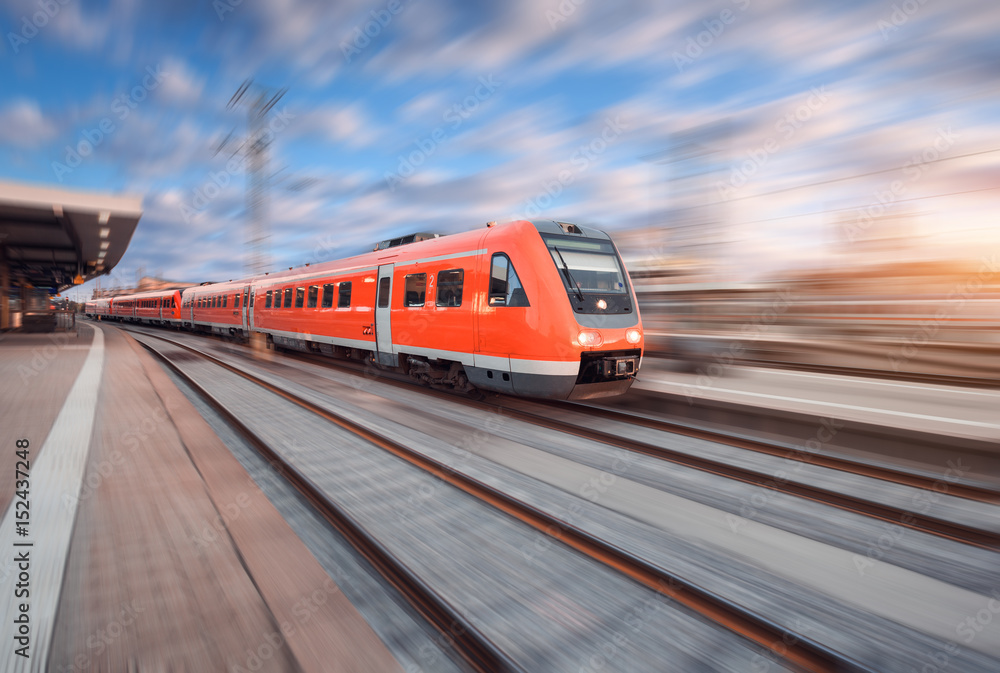 欧洲日落时分，红色现代高速列车在铁轨上行驶。火车站