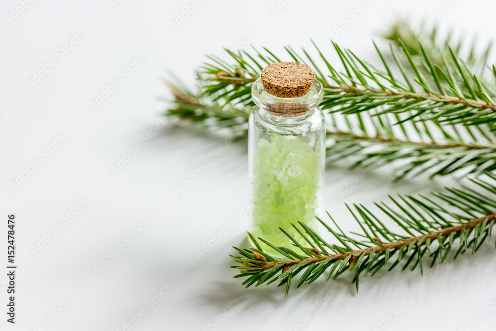 cosmetic spruce salt in bottles with fur branches on white table background
