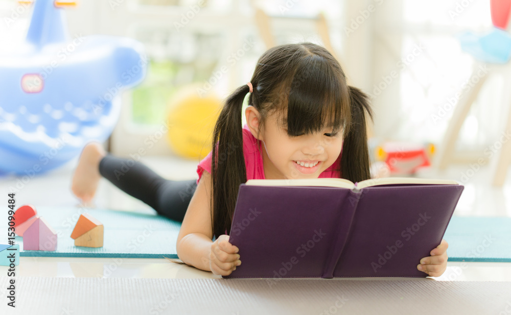 可爱的小女孩在看书。有趣的孩子在儿童房玩得很开心
