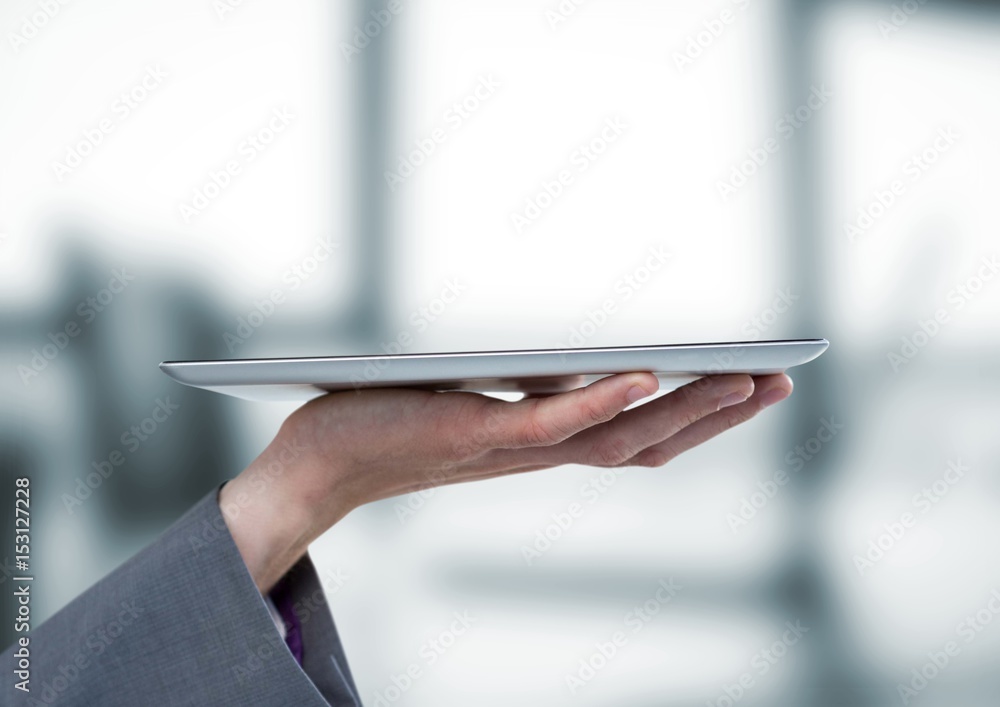 Hand with tablet against blurry grey office