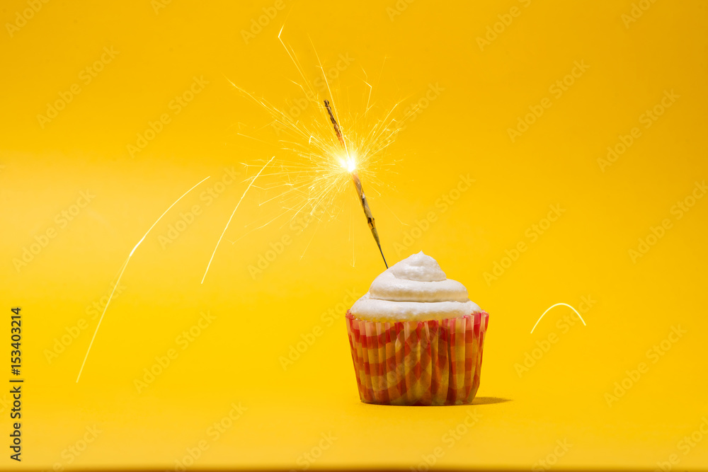 Birthday cupcake with firework on yellow background.