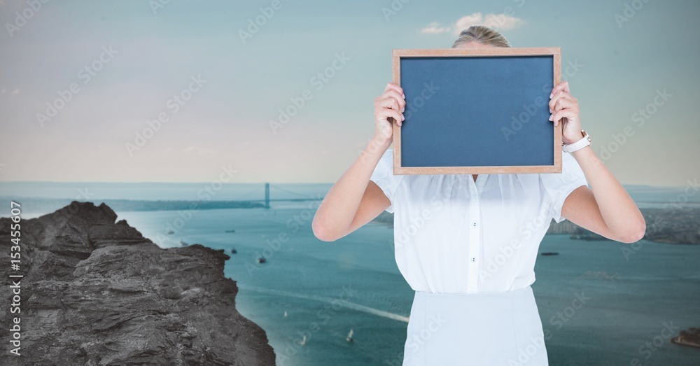Woman hiding face with slate against river
