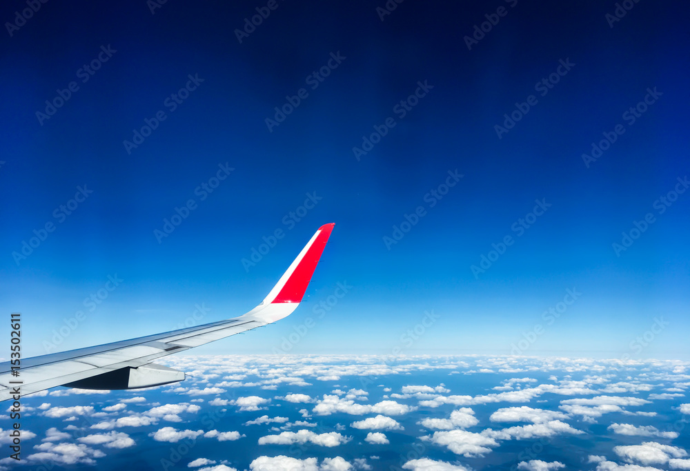 深蓝天空和机翼上的云，从飞机窗户看到的景色，带有复制空间的旅行概念