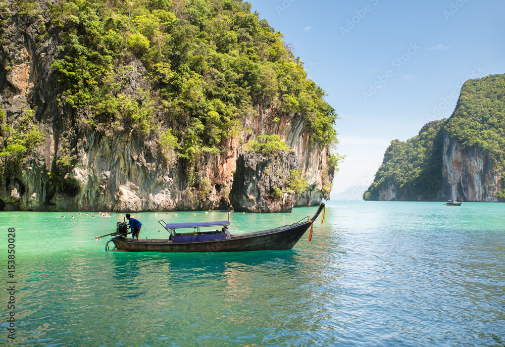 泰国普吉岛的岩石山和清澈的大海与长尾船的美丽景观。