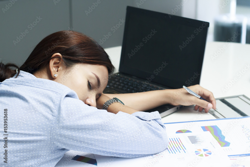 Tired business woman sleeping on desk in office
