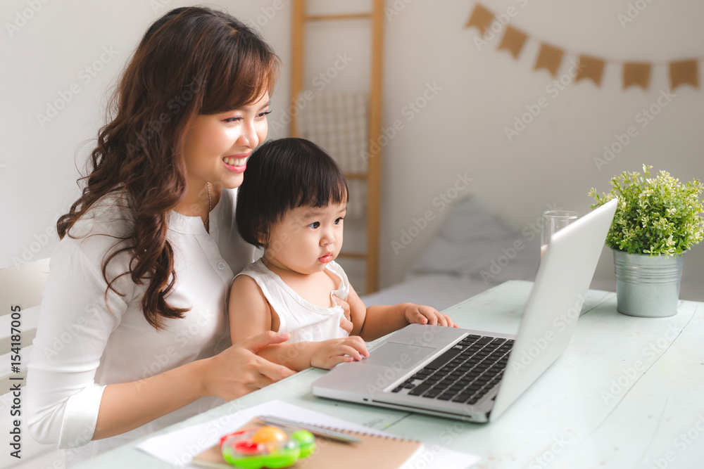 快乐的年轻亚洲妈妈和她的宝宝在网上玩游戏。