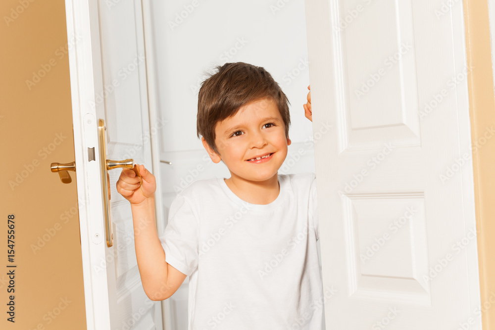 微笑的小男孩打开家里的白色门