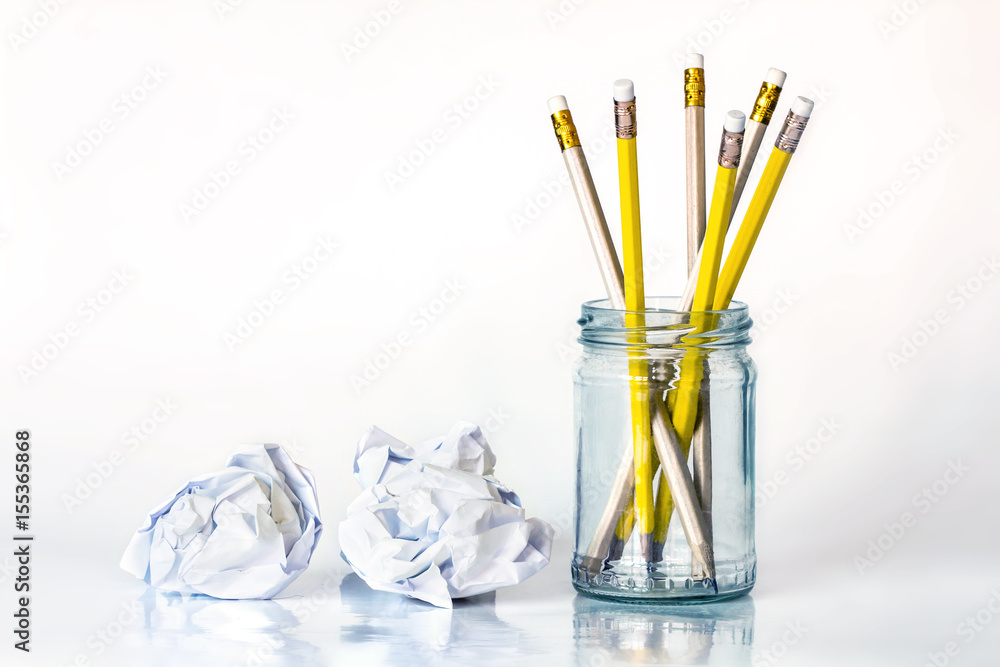 golden yellow pencil in glass jar with the crumpled paper on white background with copy space , crea