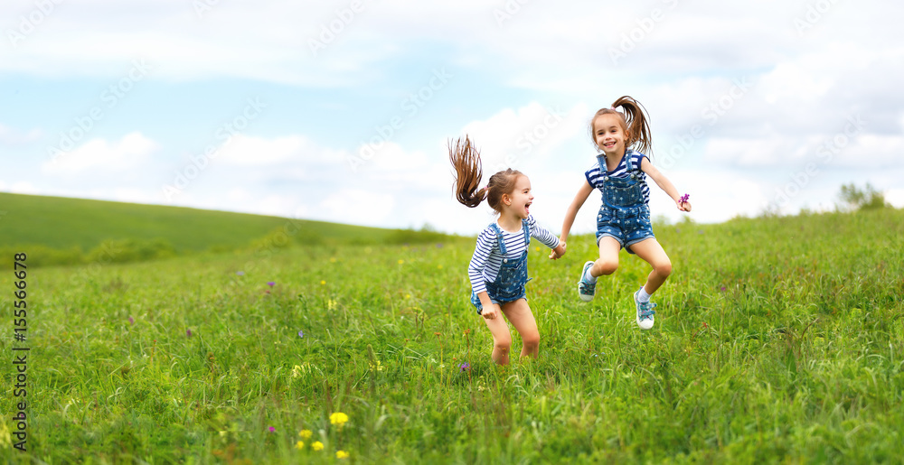 快乐的孩子双胞胎姐妹在夏天蹦蹦跳跳