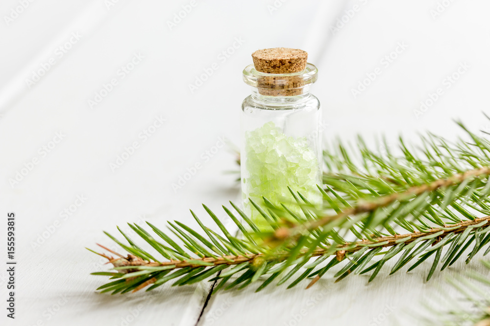 白色桌子背景上的海盐和冷杉枝瓶，用于芳香疗法和水疗