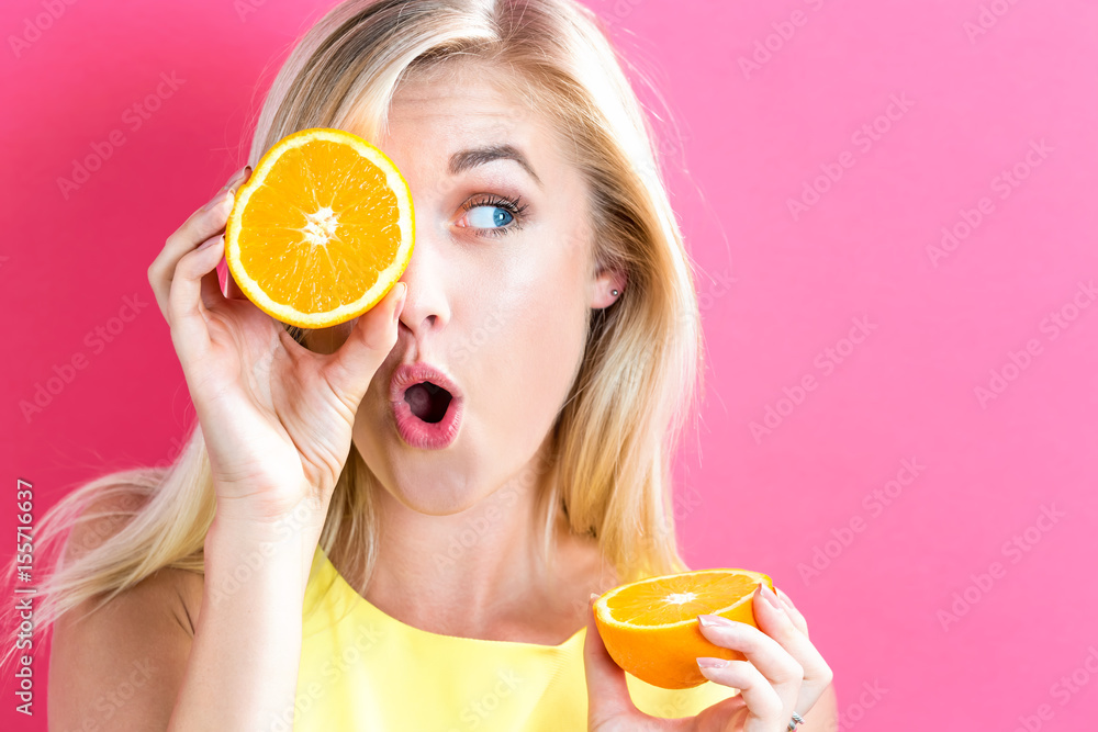 Happy young woman holding oranges halves
