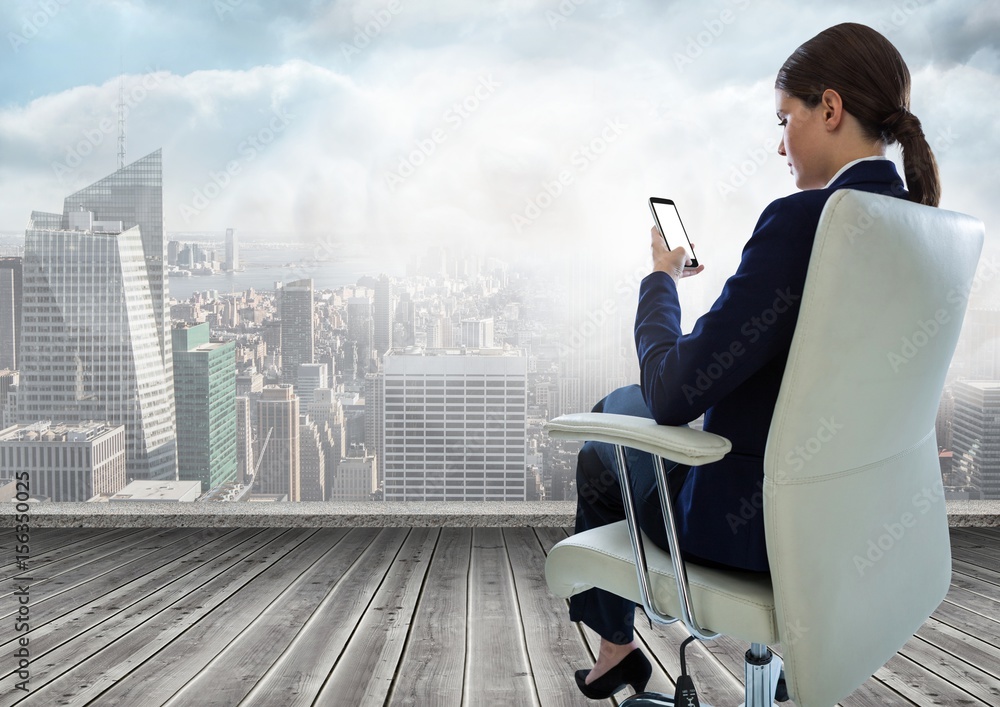 女商人坐在椅子上拿着手机俯瞰城市