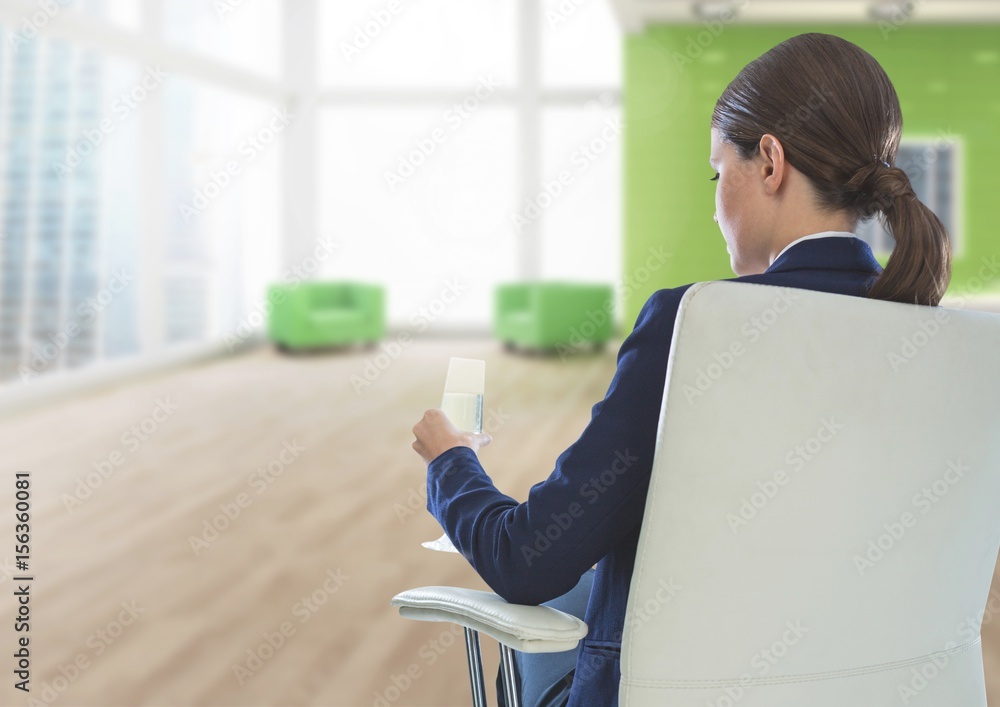 女商人坐在椅子上，拿着酒杯在办公室