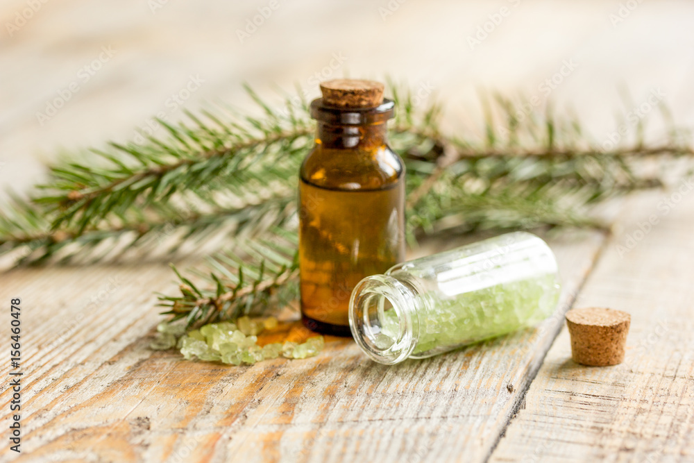 spa with organic spruce oil and sea salt in glass bottles on wooden table background