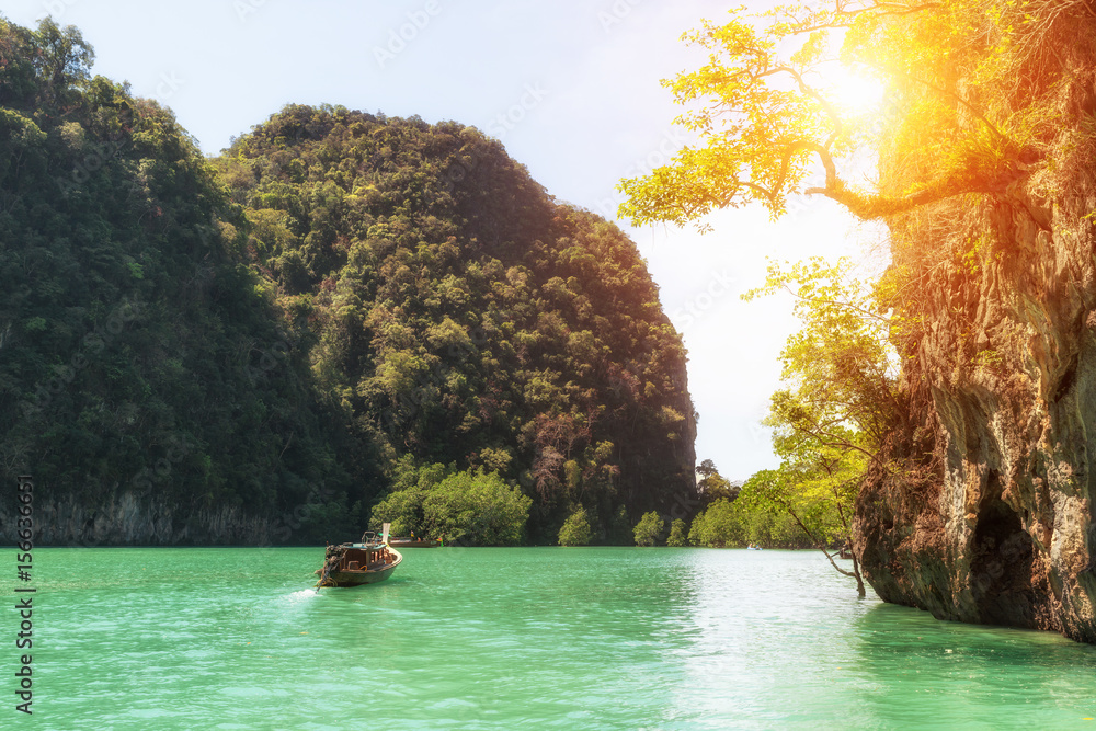 泰国普吉岛美丽的岩石山和清澈的海水景观，配有长尾船。