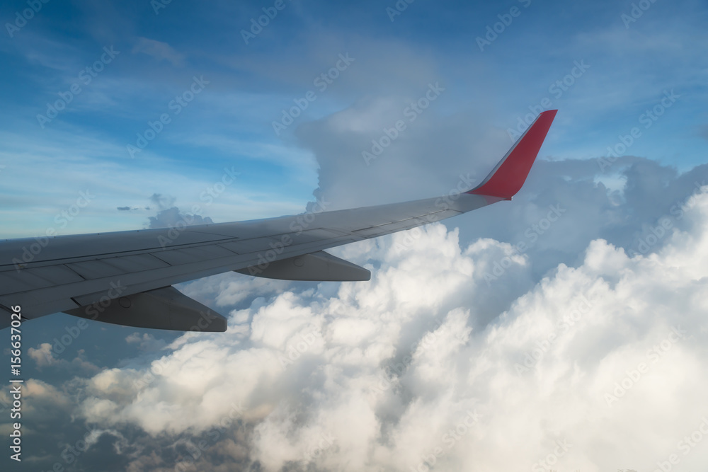 一架在云层上方飞行的飞机的机翼。人们从飞机的窗户望向天空，u